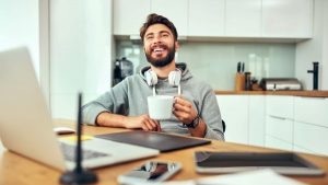 Man drinking coffee while working at home - Boosting Tax Return While Working From Home - Wealth Connexion