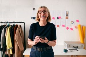 Woman With a Happy Expression With a Phone on Hand - Super Success for Women - Wealth Connexion Blog Image