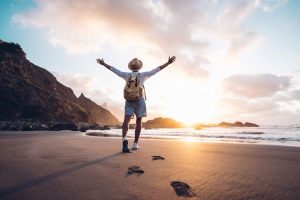 A Man Stretching His Arm Wide Open on a Beach Sunset - Design Your Own Super Adventure - Wealth Connexion Blog Image