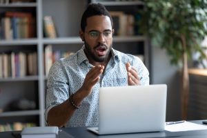 A Man Shocked Looking at His Laptop - Investment Scams - Wealth Connexion Blog Image