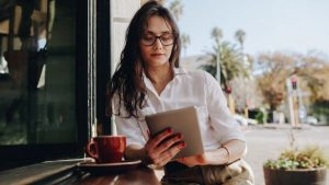 A woman looking at her tab while having coffee - Wealth Connexion