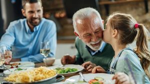 A little girl kissing an elder man on the cheeks on a dinner table - Wealth Connexion blog image