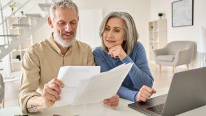 Two elderly couple looking at papers with a laptop on the table - Wealth connexion blog image