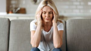 A woman sitting on a couch having a headache - Wealth Connexion blog image