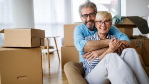 Two elderly couple sitting on the floor with moving boxes on the side and background - Wealth Connexion blog image