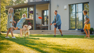 A family playing frisbee outside their house | Wealth Connexion blog image