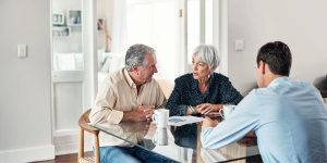 Elderly couple sitting at a table discussing advice with a professional.