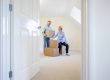 Senior Couple Downsizing In Retirement Carrying Boxes Into New Home On Moving Day