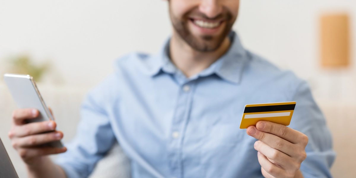 WealthConnexion_251118 Happy man with smartphone and credit card shopping online